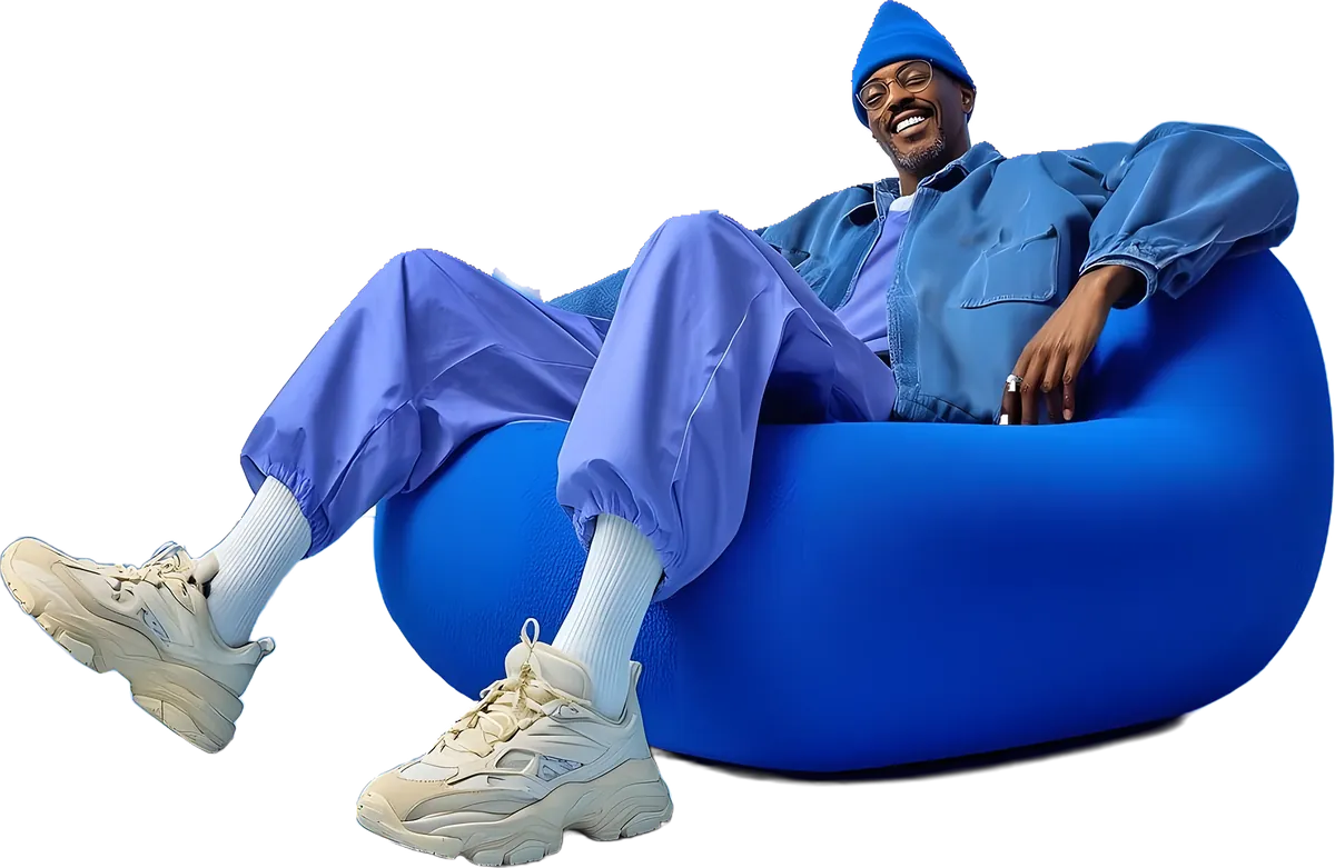 Smiling man in blue denim relaxing on a bean-bag chair with his phone